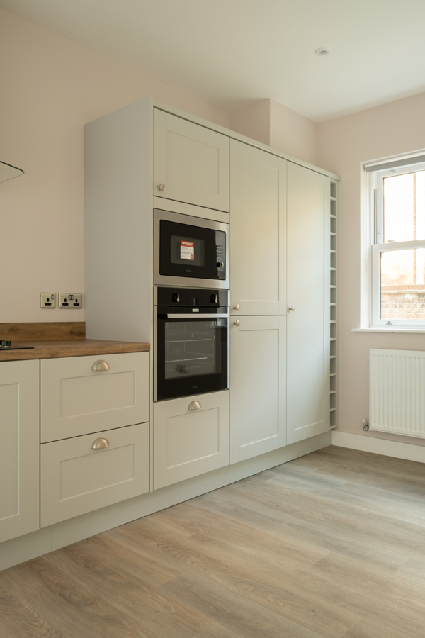 A light and airy kitchen with classic white cabinet doors and a mid-colour wood top